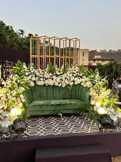 A luxurious green velvet sofa becomes the centerpiece of this photo spot, surrounded by white flowers, disco balls, and a modern geometric backdrop.