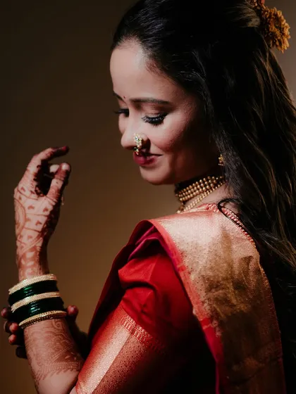 A classic bridal portrait from the side, highlighting the bride's elegant profile, her intricate nath, and the floral accessory in her hair.