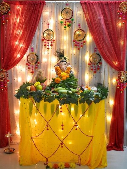 A traditional decoration using red and yellow fabrics with dreamcatcher-style hangings. The fairy lights in the background add a warm and festive glow.