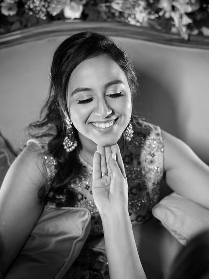 A tender black and white portrait of a guest gently touching the bride's chin, a moment of quiet affection.