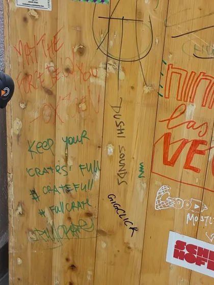 A close-up of the graffiti and messages on the booth. Every mark has a story, from "Keep your 'crates' full" to tags from visiting artists.