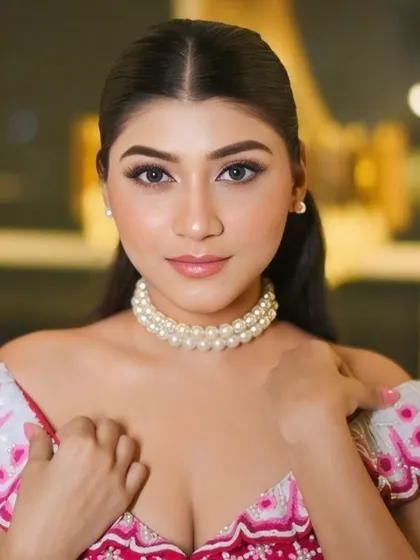A glamorous, glassy makeup look with a pop of pink. The off-shoulder blouse and pearl choker add a modern, chic touch to this festive style.