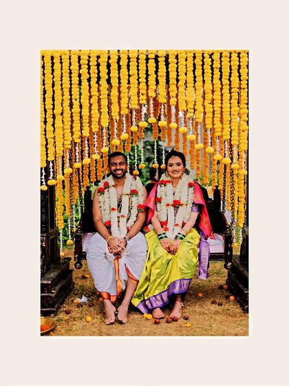 Alisha and Venkat seated on a swing decorated with marigolds, a classic and colorful South Indian wedding portrait.
