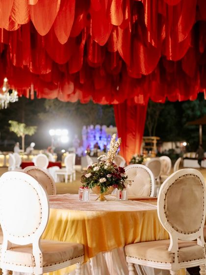 Another view of the guest tables under the red petal ceiling, showing the warm and inviting ambiance created by the decor.
