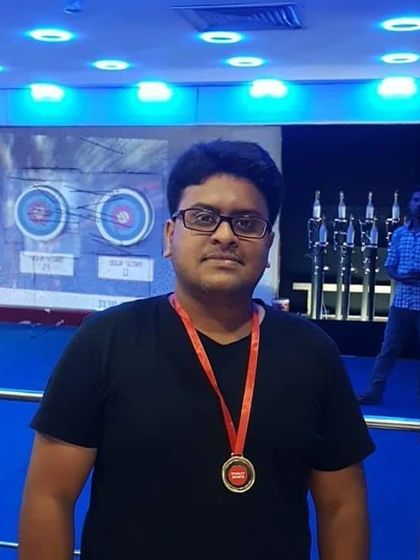 Standing proudly with his medal in our blue-lit, modern facility. The unique ambiance adds to the fun of the archery experience.
