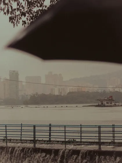 A glimpse of the Powai lake and the distant Hiranandani skyline through a frame of an umbrella. This shot captures the quiet, personal experience of enjoying the Mumbai rains.