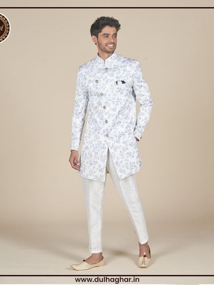 A full-length view of a white floral printed Indo-Western jacket paired with white trousers and traditional juttis.