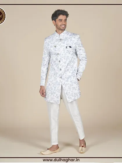 A full-length view of a white floral printed Indo-Western jacket paired with white trousers and traditional juttis.
