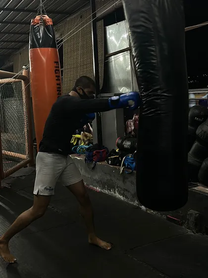 A fighter demonstrates a powerful right cross on the heavy bag. This photo captures the focus and technique required to generate knockout power in boxing.