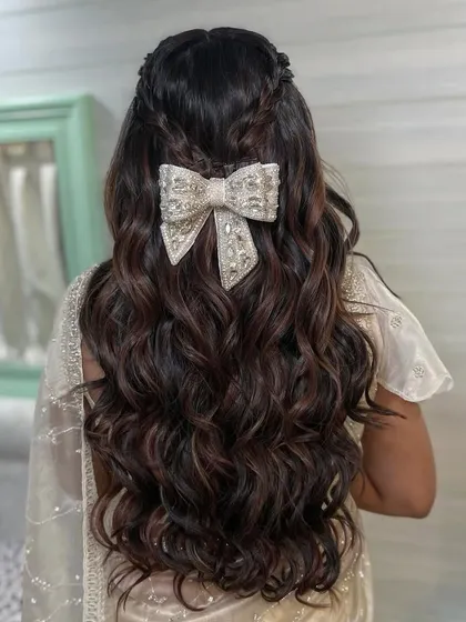 I love when brides want to add a playful and modern touch to their look. This half-up style with soft, flowing waves gets a chic update with a beautiful oversized bow accessory. It’s a perfect hairstyle for a Roka ceremony or an engagement party, blending romance with contemporary fashion.