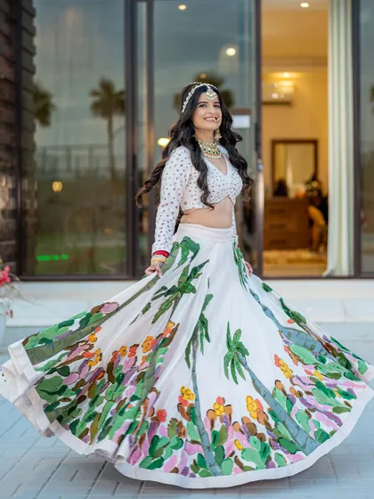 A joyful, twirling shot of the bride, showing off the beautiful flare of her hand-painted lehenga. A perfect capture of bridal happiness.