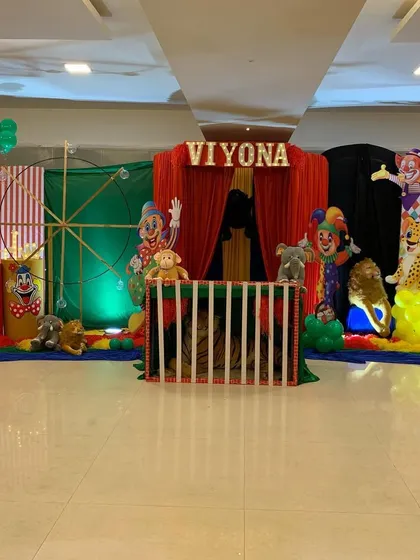 A fun carnival themed birthday party. The stage is set with red, green, and black curtains, circus animal props, and a caged area for a touch of authenticity.