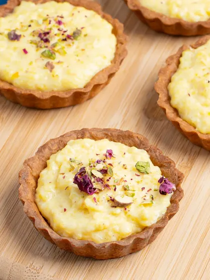 Close-up of a Shrikhand Tart, a fusion dessert. We highlight the creamy texture and pistachio garnish, making it look like a gourmet treat.