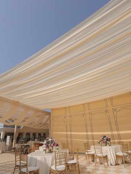 The dining setup for the pheras lunch, with soft fabric draping overhead to provide shade from the winter sun while maintaining an airy, open feel.