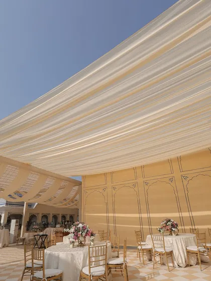 The dining setup for the pheras lunch, with soft fabric draping overhead to provide shade from the winter sun while maintaining an airy, open feel.