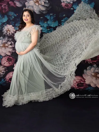 Like a fairy tale queen. This flowing mint green gown with its ruffled train adds so much texture and movement, creating a truly magical and unforgettable maternity portrait.