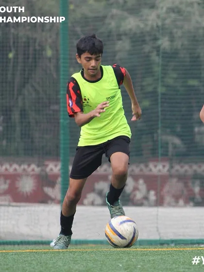 A young player in a training bib focused on his next move. This captures the concentration required during our skill development drills.