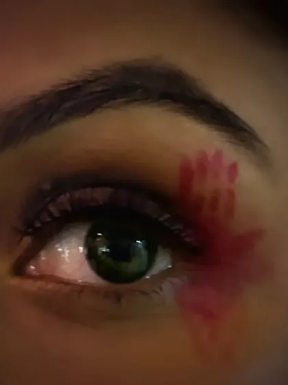 A macro shot of the eye from a Halloween look, featuring a tiny, hand-painted bloody handprint. It's these small details that make a creative look truly stand out.