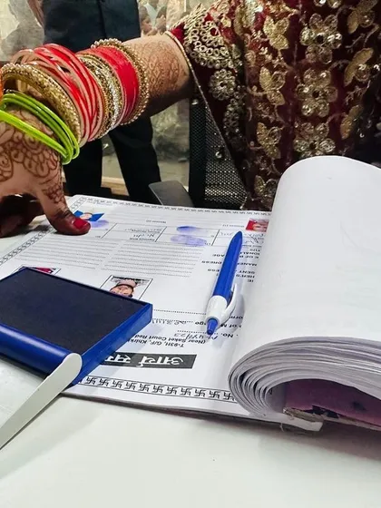 The official signing of the marriage register is a significant moment. This close-up shot shows a bride, adorned with traditional bangles and henna, making her union legally binding.