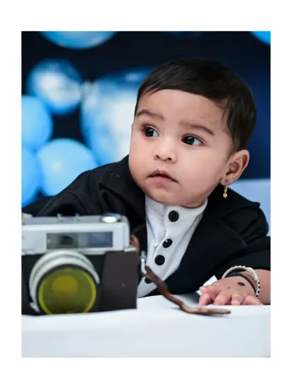 A close-up portrait from a six-month photoshoot, capturing this baby's thoughtful expression as he interacts with a vintage camera prop. These detailed shots focus on your baby's adorable features.