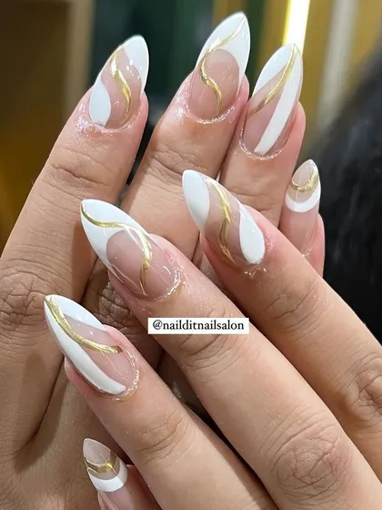 A classy and artistic design with white and gold abstract shapes on long almond nails. The use of negative space and clean lines creates a very modern and stylish look.