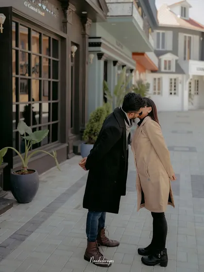 An intimate kiss shared between a couple on a stylish, European-inspired street.
