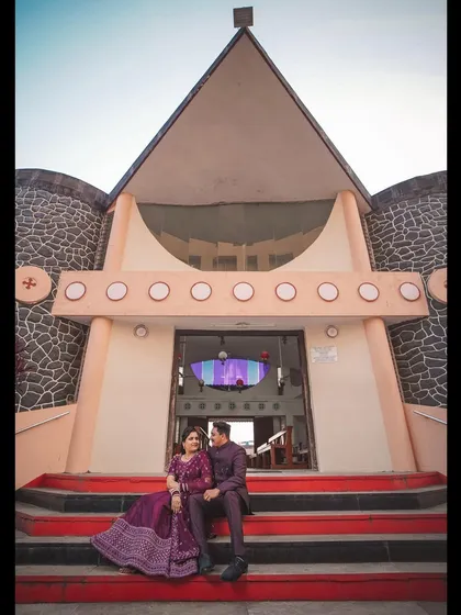 A grand, wide-angle shot of the couple sitting on the steps of the church after their wedding. This photo captures the impressive architecture of the church and the couple's happy moment.