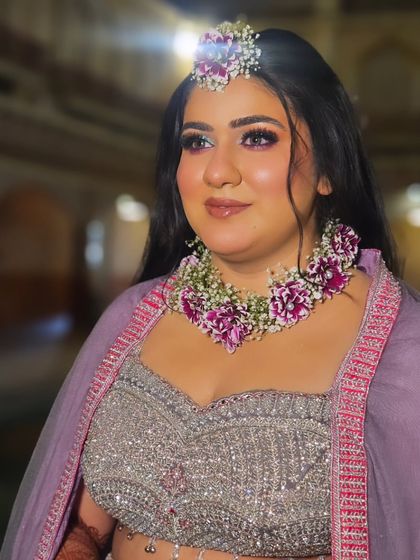 A close-up portrait of the bride. The purple flowers in her jewellery are complemented by the soft purple tones in her makeup.
