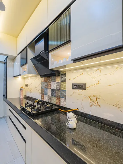 I design modular kitchens that are both beautiful and highly practical. This one features sleek handleless cabinets, a durable granite countertop, and a patterned tile backsplash that adds a unique touch, all lit perfectly for an efficient cooking experience.