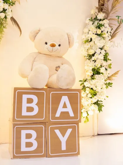 A cute teddy bear sitting on 'BABY' blocks is a classic and charming prop for any baby shower. It adds a touch of innocence and playfulness to the celebration.