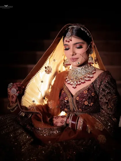 This shot uses a single light source from below to illuminate the bride's face and the details of her dupatta.