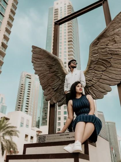 A creative shot of the couple posing with the iconic Wings of Mexico sculpture and the Burj Khalifa.