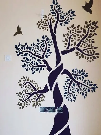 A two-tone tree stencil adds a touch of nature-inspired art to this room. This technique allows for subtle yet impactful wall decor that complements the existing interior design without overwhelming the space.