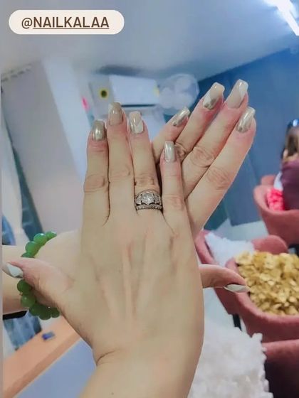 A chic set of long, square nails with a metallic silver-gold finish and subtle heart accents.