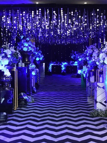 A dramatic, fully immersive entrance for a "starry night" themed Sangeet, with a chevron walkway, deep blue lighting, and a ceiling of hanging silver sequins.