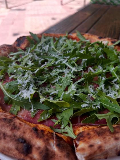 A close-up on the fresh arugula and shaved parmesan that top our Parma Ham pizza.