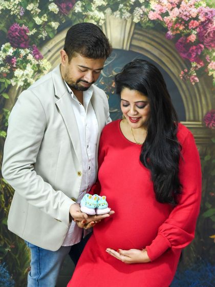 A sweet couple's portrait in our floral studio, holding up a tiny pair of baby shoes.