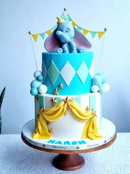 A full, two-tiered Dumbo-themed carnival cake, showing the combination of patterns and the cute topper.