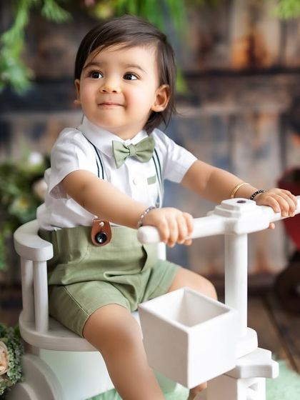A close-up of a happy boy on his tricycle. His bright smile and dapper outfit make this a truly heartwarming milestone portrait.