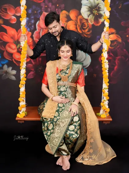 A beautiful couple portrait on a swing against a floral backdrop. The traditional attire and loving pose make this a perfect memory of their journey together.