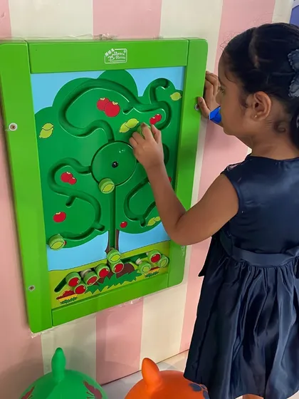 A young girl fully engaged with our tree-themed wall maze puzzle.