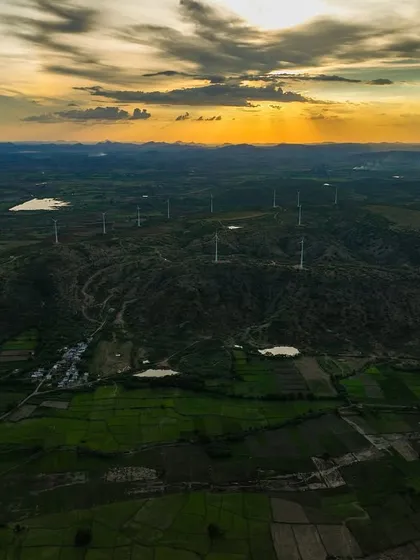 Rural Karnataka at sunset, with a field of windmills on the hills. A beautiful blend of nature and renewable energy.