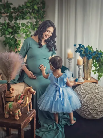 A magical moment between mother and daughter. The little girl reaches out to touch her mother's belly, curious about the new life growing inside. A truly precious memory captured.