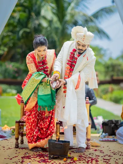The couple participates in a traditional wedding ritual, pouring rice as a symbol of prosperity and togetherness.