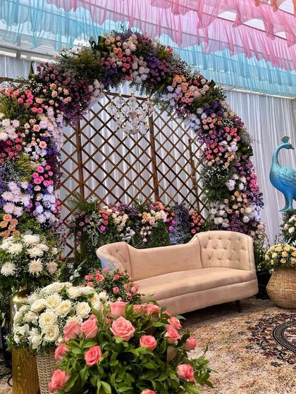 A lush and floral Mehendi setup, with a beautiful arch and a peacock prop adding a touch of whimsy and color.
