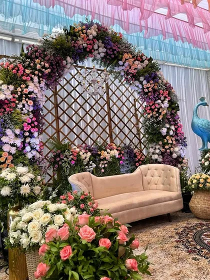 A lush and floral Mehendi setup, with a beautiful arch and a peacock prop adding a touch of whimsy and color.