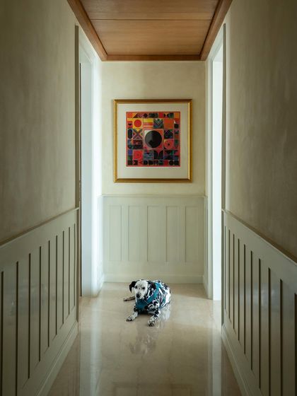 A hallway can be a destination in itself. Here, wainscoting, a wood-paneled ceiling, and a vibrant piece of art create a gallery-like feel. The family's dalmatian seems to approve.