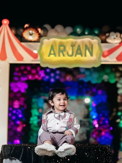 The star of the show. A beautiful shot of the birthday boy sitting in front of his personalized sign at his fun-filled carnival party.