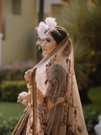 A side profile of the bride, her beautiful embroidered veil framing her face. The soft light creates a gentle and romantic mood.