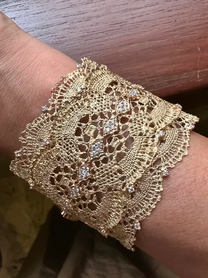 A close-up view of my signature lace cuff, worn on the wrist. This piece is inspired by delicate Chantilly lace and is meticulously hand-woven from 18k yellow gold, with natural diamonds scattered like dewdrops to catch the light.